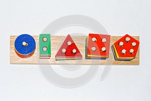 Wooden toy for baby, children isolated on white background. Shapes of different colors and sizes with holes