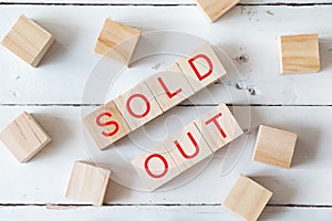 Wooden toy blocks with words SOLD OUT in red color on white wooden background