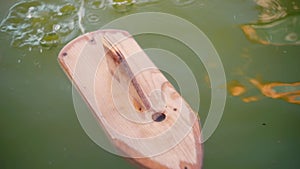 A wooden toy boat floats in the pool