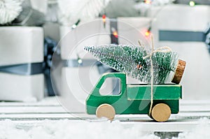 Wooden toy car carrying a christmas tree on shiny lights background