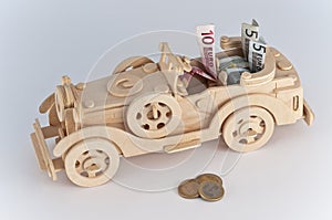 Wooden toy car with coins and euro bills inside