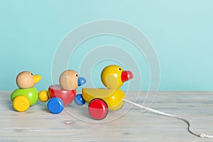 Wooden toy ducks a kids toy to pull around against a blue background with space for copy