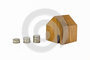 Wooden toy house with coins concept of dearness of habitation photo
