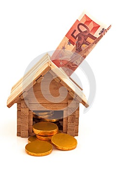 Wooden toy house with euro paper money and gold coins