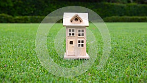 Wooden toy house on grass. The concept of selling, buying, renting real estate, family home, insurance. Dream home.