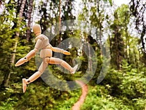 Wooden toy mannequin in the forest among grass and trees in summer, autumn, spring. The concept of outdoor recreation