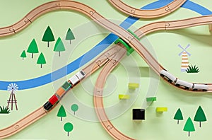 Wooden toy railway with a train, top view. Children toys, a train with wagons traveling in a green meadow with a river.