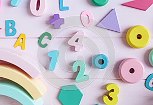 Wooden toy rainbow, numbers, blocks, pastel color arc on pink background. Natural no plastic toys for creativity development