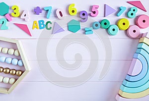 Wooden toy rainbow, numbers, blocks, pastel color arc on pink background. Natural no plastic toys for creativity development.
