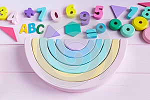 Wooden toy rainbow, pastel color arc   on light pink background. Natural  no plastic toys for creativity development.