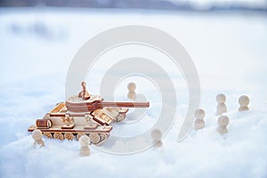 A wooden toy Russian tank T-34 and little men in the snow. Russia and Ukraine are at war in winter. Encirclement photo