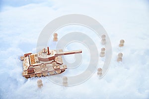 A wooden toy Russian tank T-34 and little men in the snow. Russia and Ukraine are at war in winter. Encirclement photo