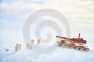 A wooden toy Russian tank T-34 and little men in the snow. Russia and Ukraine are at war in winter. Encirclement photo