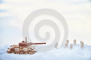 A wooden toy Russian tank T-34 and little men in the snow. Russia and Ukraine are at war in winter. Encirclement photo