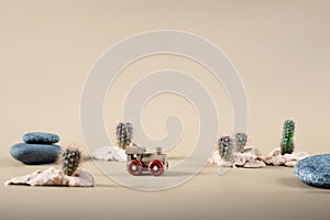 Wooden toy steam locomotive in desert with stones and cactuses on beige backdrop