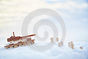 A wooden toy tank and little men in the snow. Russia and Ukraine are at war in winter. Encirclement, retreat, attack photo