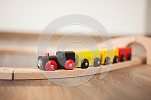 Wooden toy train on railroad with wooden bridge. Clean laminated floor