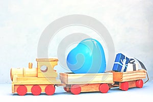 Wooden toy train with some gifts and blue heart shaped balloon. Greeting card for Birthday, Mather`s day, Father`s Day