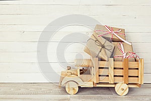 Wooden toy truck with gift boxes in the back on a white wooden b