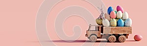 Wooden toy truck loaded with colorful Easter eggs on pink background with copy space