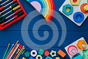 Wooden toys, calculation rack, shape sorter board on classic blue background. Back to school background. Close up. Top view