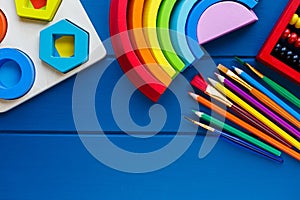 Wooden toys, cubes, brushes on classic blue background. Back to school background. Close up. Top view, copy space. Education