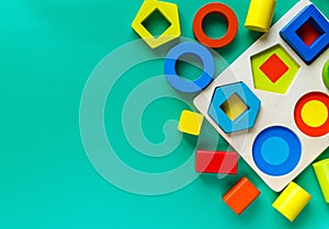 Wooden toys, shape sorter board on green background. Back to school. Close up. Top view, copy space. Education