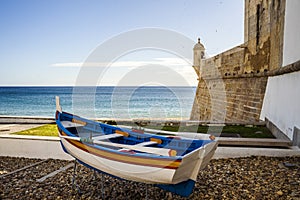 The wooden traditional boat and Saint James Fortress on the beach of Sesimbra, Portugal