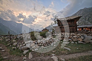 Wooden traditional house with rock wall during sunset at mountain top.