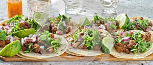 Wooden tray with carne asada tacos on corn tortilla