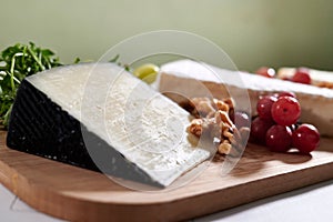 Wooden tray filled with an assortment of fresh grapes and various types of cheese