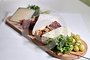 Wooden tray filled with an assortment of fresh grapes and various types of cheese