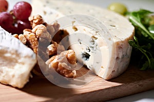 Wooden tray filled with an assortment of fresh grapes and various types of cheese