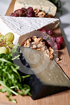 Wooden tray filled with an assortment of fresh grapes and various types of cheese