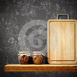 Wooden tray and jars with fruit on wooden shelf. Copy space for your decoration and products. Dark gray retro wall background.