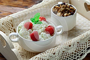 Wooden tray with tasty breakfast : cottage cheese with fresh raspberries and granola.