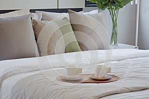 Wooden tray of tea set on bed in modern bedroom