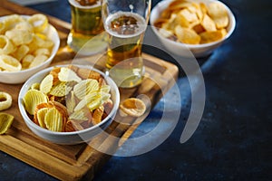 On a wooden tray, two glasses of light beer, potato chips, onion rings. A classic set of sports fans. Watching sports programs on