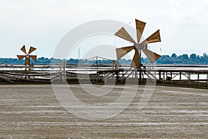 Wooden turbine at salt pan using for press seawater up to field with blue sky background in summer time of Thailand,South East