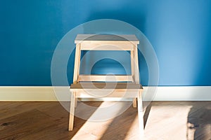 Wooden two step ladder stool with blue matte wall background