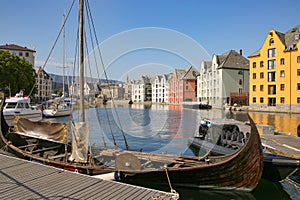 Wooden viking boat moored at the pier in the city centre of Alesund, Norway.