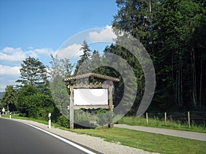 A wooden vintage advertising sign stands on the road with a white isolated place for writing or advertising