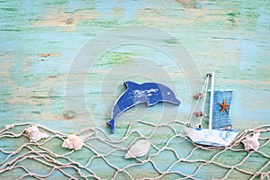 Wooden vintage boat, dolphin, fishnet and sea shells over blue background