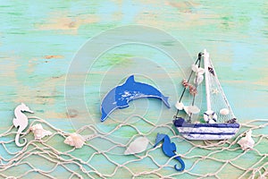 Wooden vintage boat, dolphin, fishnet and sea shells over blue background