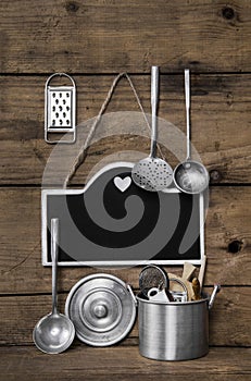 Wooden vintage kitchen background with old kitchenware, blackboard and spoons for cooking fans.