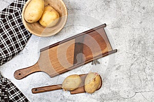 Wooden vintage mandoline and potatoes on a marble table