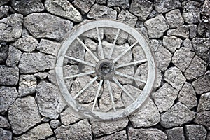 Wooden wagon wheel on a stone back ground.