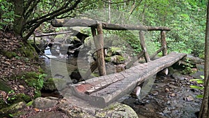 Wooden walking bridge over a creek and waterfall in the woods