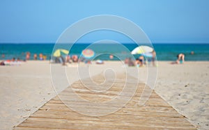 Wooden walkway on a beach with tourists and umbrellas with the s