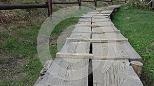 A wooden walkway leads to the top of mountain with grass and wooden fence